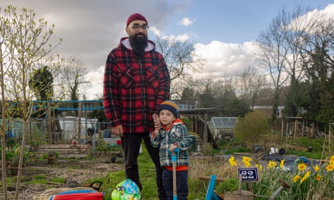 Azeem Choudhry and Ibrahim standing on their plot. Ibrahim is holding a child’s spade, and his bike is in the foreground