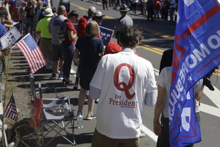 A man in a QAnon T-shirt walks among Trump supporters as they wait for Donald Trump to arrive and visit Mariotti Building Products in Old Forge, Pennsylvania, in August.