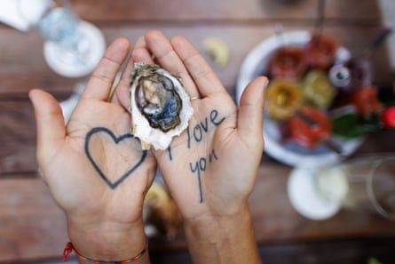 Hands hold an oyster, with ‘I love you’ written on one palm and a heart drawn on the other. 