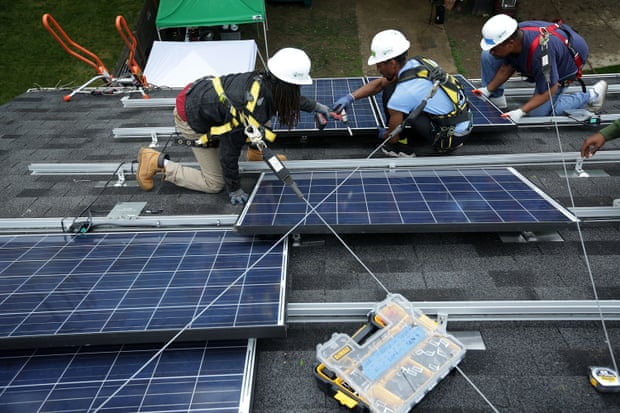 Workers install solar panels in Washington, DC. A boom in solar and wind power jobs in the US led a global increase in renewable energy employment. 