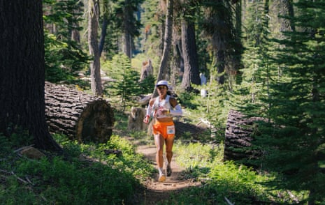 Jenn Lichter runs on a forest trail lined with fallen logs and pine trees