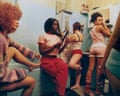Five women in a bathroom, each performing a different task such as painting toenails or curling hair