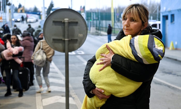 A woman carries a child on arrival to the border of Ukraine-Slovakia, after Russia launched a massive military operation against Ukraine, in Vysne Nemecke, Slovakia.
