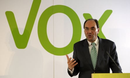 Alejandro Vidal-Quadras speaking in front of a green Vox sign