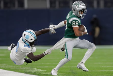 NFL Academy player Raul Khalifa from Finland desperately tries to stop Kai Wilson of De La Salle by grabbing his shirt tail.