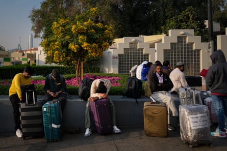 People sat next to their luggage outside the airport