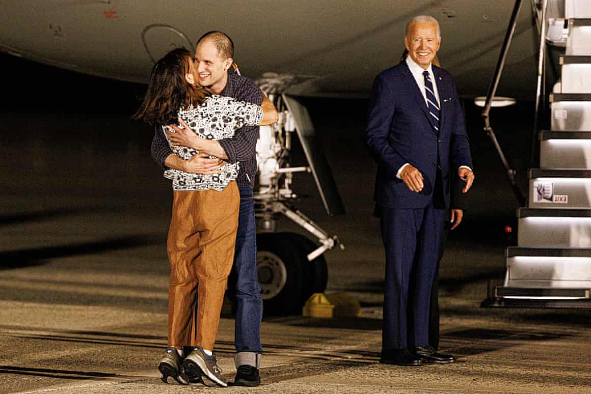 Evan Gershkovich hugs family members as President Joe Biden looks on next to aeroplane steps