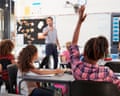 Classroom with teacher pointing at girl with her hand up