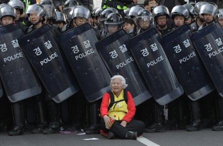 A woman sits in front of riot police blocking the road to protect protesters during the anti-government protest on April 24, 2015 in Seoul, South Korea