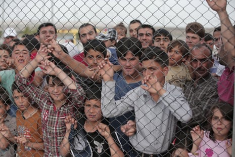 Syrian refugees stand behind a fence at a camp in south-eastern Turkey