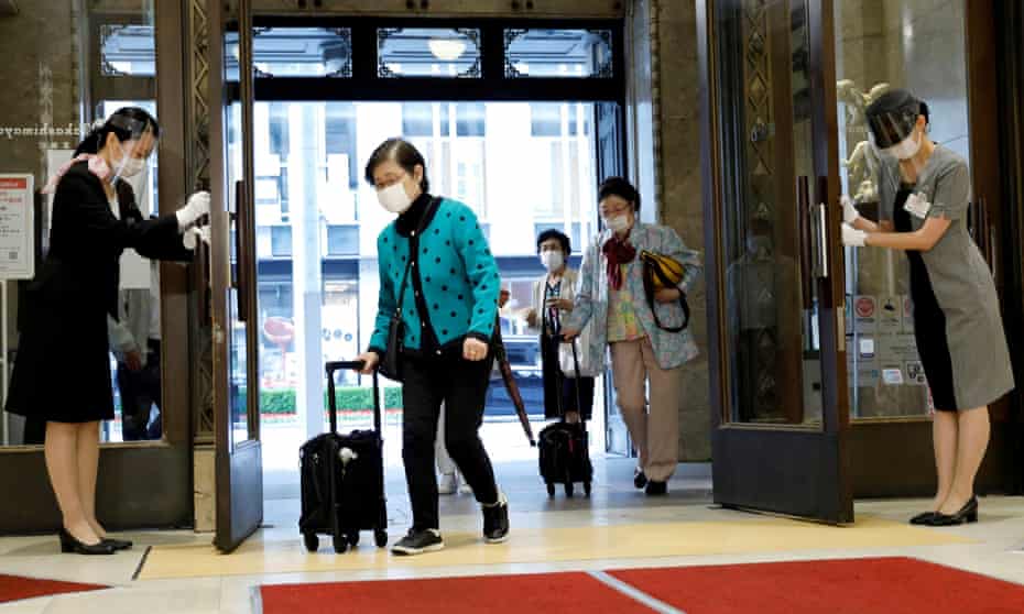 Staff members wearing face masks and shields bow to customers as the Nihombashi Takashimaya shopping centre partially reopens in Tokyo.