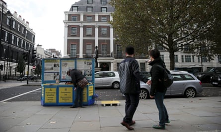 A woman cleans an information kiosk about Falun Gong outside the Chinese embassy in London