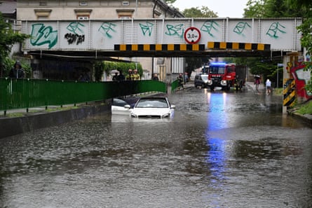 Submerged vehicle in flood waters, with fire engine in background