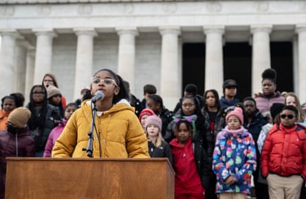 girl at podium as other kids watch from memorial stairs