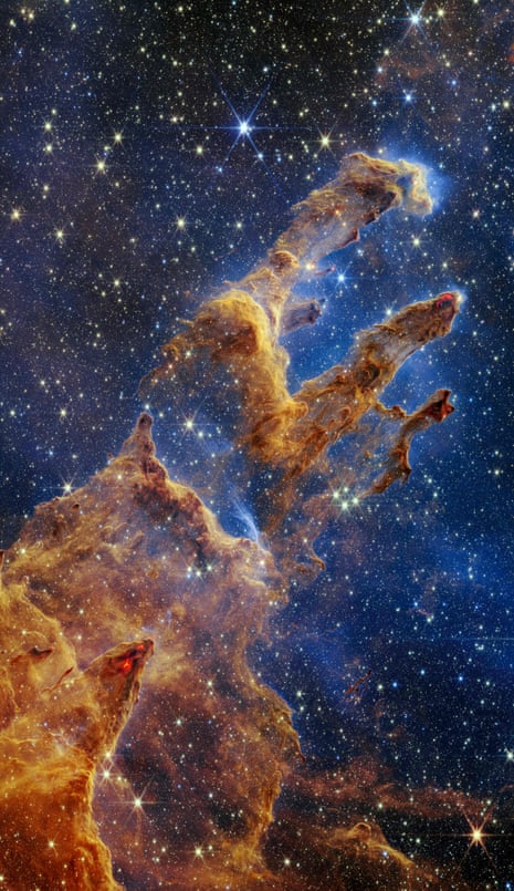 An image of the Pillars of Creation, the pillars look like arches and spires rising out of a desert landscape, but are filled with semi-transparent gas and dust, against a star-filled dark blue background