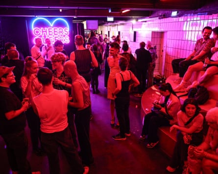 People in a nightclub standing talking bathed in red light