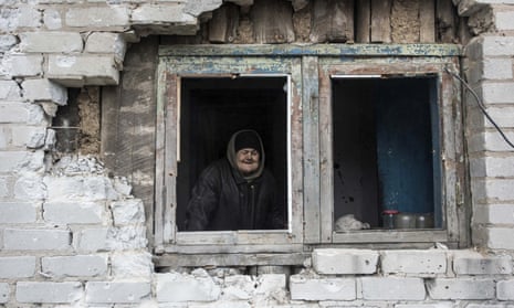 An elderly woman looks through the window in her house damaged by shelling in Avdiivka, eastern Ukraine.