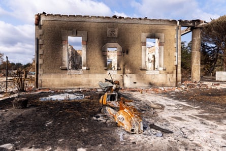 A burned out house with a destroyed moped in front