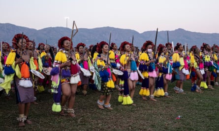 Women wearing skirts, brightly coloured tassles, anklets, headwear and carrying swords dance and sing in lines