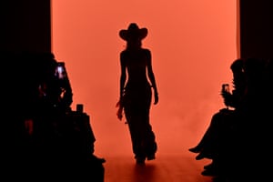 A model in a cowboy hat in silhouette on the runway
