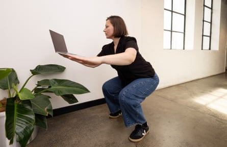 Emma attempts squats while holding a laptop