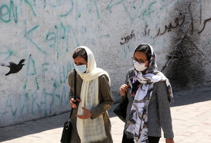 Women wearing face masks walk down a street in Tehran on Sunday.