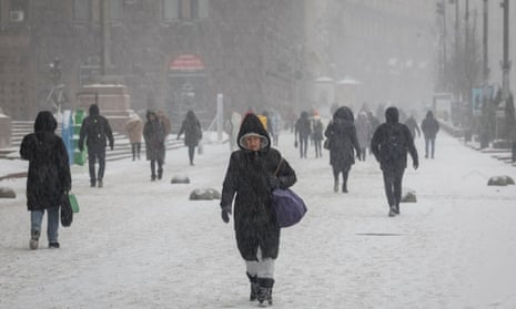 People walk down a street amid a snowfall in central Kyiv.