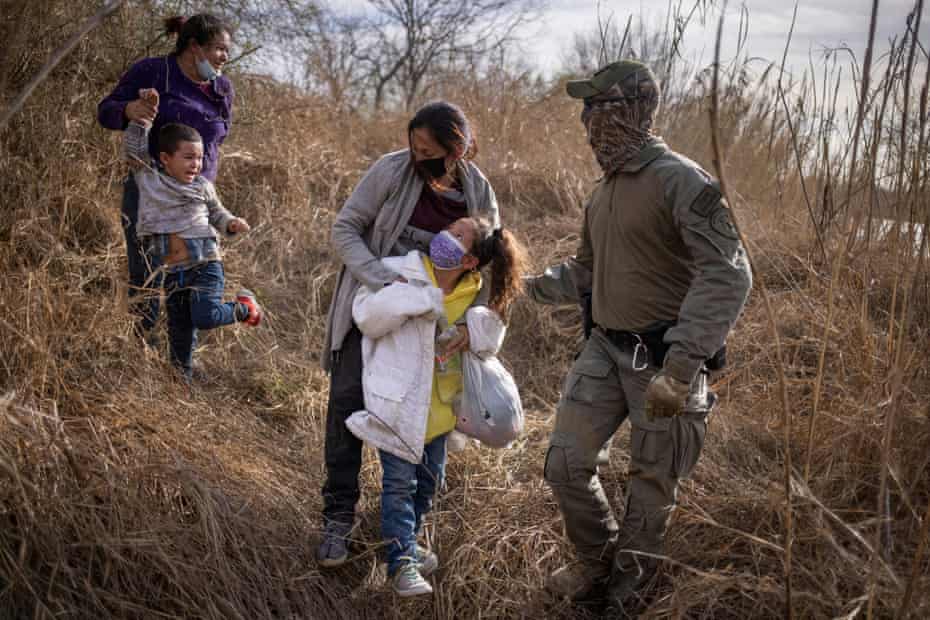 Migrants are escorted out of the brush after crossing Rio Grande river in Penitas, Texas, on Tuesday.