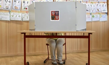 A woman sits behind a screen at a voting booth