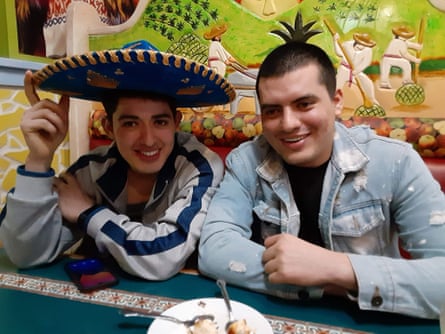 Brothers Gerson (in hat) and Henoch Turcios sitting side by side at a table, smiling