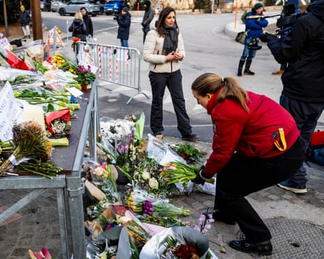 A woman lays flowers at the scene