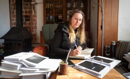 Kate Wilson at her desk surrounded by binders full of papers and photographs