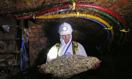 A sewer worker holding a fatberg