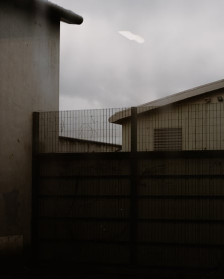 Buildings join a wall with a wire fence on top