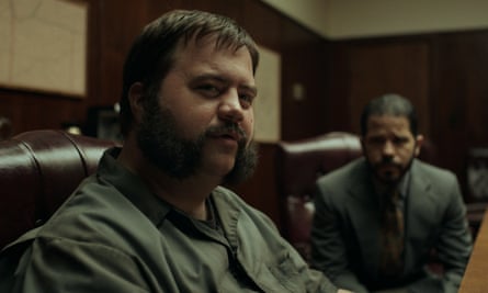 Man with beard sits in front of man wearing suit.