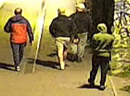 Image of men from behind walking along a street-lit road