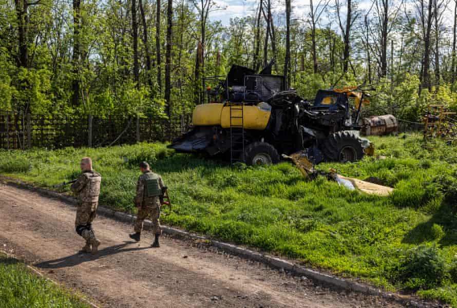 Ukrainian soldiers pass farm equipment destroyed by Russian tanks in Cherkska Lozova, Ukraine.