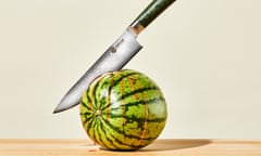 A large knife embedded in a melon, with juice flowing from the cut.
