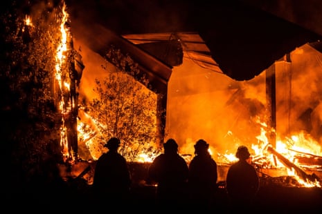 Firefighters look on as a structure burns during the Kincade fire off Highway 128, east of Healdsburg, California, on Tuesday..