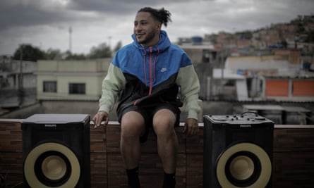 The artist Hebert Amorim sits between two big speakers of a funk soundsystem