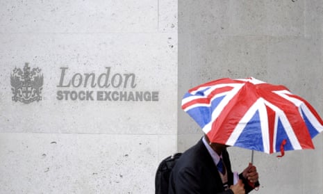 A worker shelters from the rain with a union flag umbrella as he passes the London Stock Exchange in London