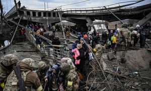 People cross a destroyed bridge as they evacuate the city of Irpin, northwest of Kyiv, during heavy shelling and bombing on Saturday.