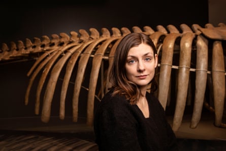 A middle-aged woman standing next to the rib cage of a skeleton of a large animal