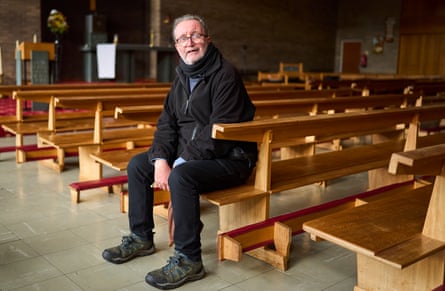 Father Chris Hughes seated on a pew inside a church