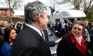 Gordon Brown surrounded by press puts his hand on Gillian Duffy's shoulder who looks outraged