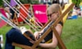 A young woman reads a book in a deckchair on fake grass at Hay literature festival