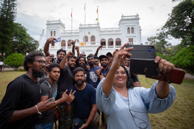 Para pengunjuk rasa berpose untuk selfie bersama saat mengembalikan Kantor Perdana Menteri ke otoritas pemerintah.