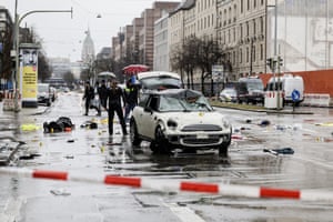 Police work near a damaged Mini in the middle of a road