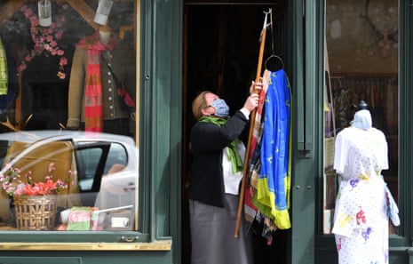 A woman wearing a face mask arranges her shop in Salzburg, Austria, after it re-opened today as the government eased nationwide lockdown measures