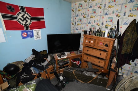 Bedroom with a pile of guns on the floor and a Nazi flag on the wall